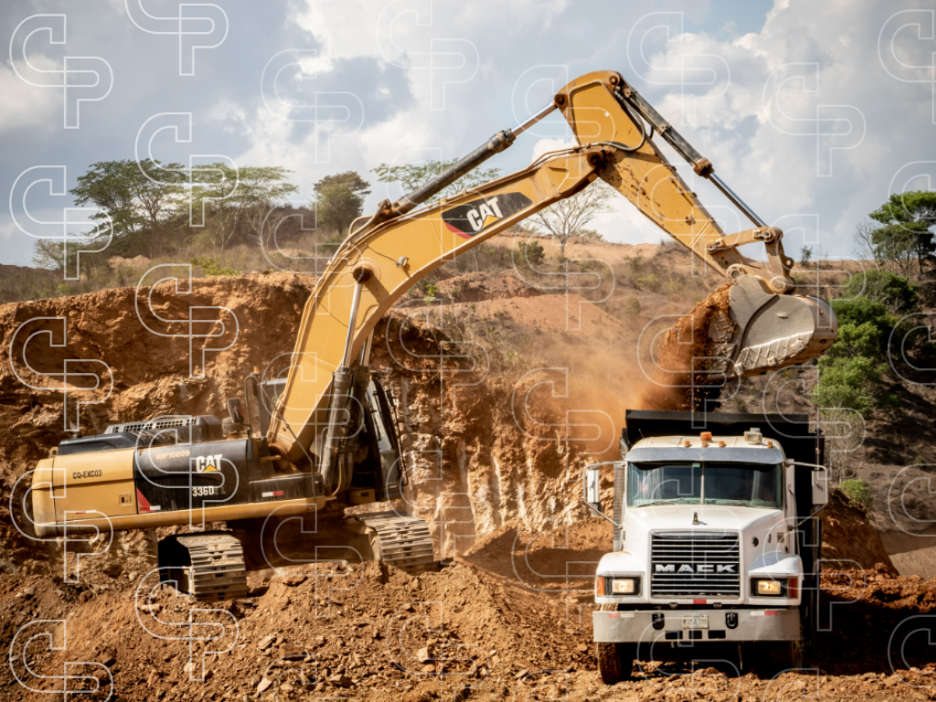 Large excavator loading rock and earth into a dump truck at an open pit mine or quarry.