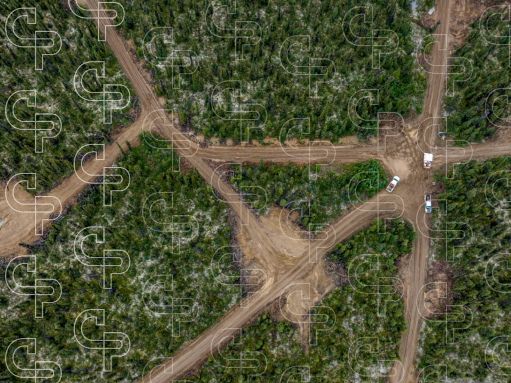 Aerial view of winding mine access roads cutting through dense green forest and vegetation.