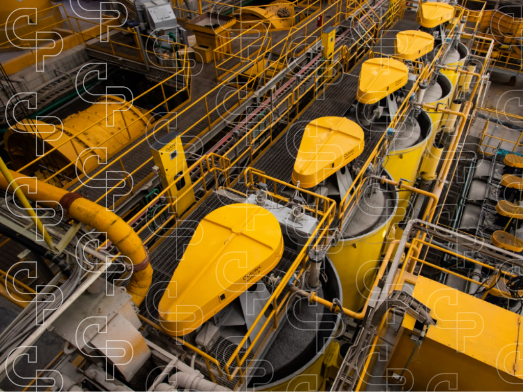 Overhead view of yellow flotation cells, safety railings, pipework and platforms inside a mineral processing plant.